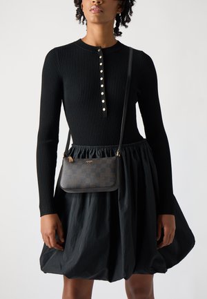 Black ribbed dress with long sleeves and button detail at the neckline, paired with a small, dark checkered crossbody bag.