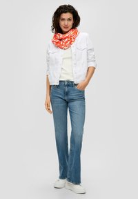 Witte spijkerjack, crèmekleurige top en lichtblauwe flared jeans. Feloranje sjaal met patroon. Witte platform sneakers. Casual outfit.