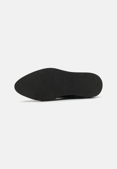 Semelle de chaussure noire avec une texture lisse et une forme pointue. Le dessous est plat avec un minimum de détails et un design épuré et discret.