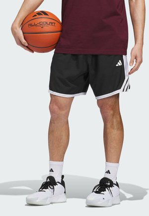 Person, der holder en orange Adidas basketball iført en vinrød skjorte, sorte Adidas shorts, hvide Adidas sokker og hvide Adidas sneakers.