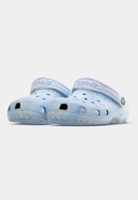 Light blue Crocs clogs with a marbled pattern, featuring ventilation holes, a back strap, and "CROCS" embossed on the side.