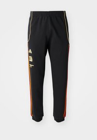 Black athletic pants with elastic waist, gold and red side stripes, and yellow logos on the left thigh.