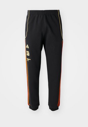 Crne sportske hlače s elastičnom stražnjom, zlatnim i crvenim bočnim trakama, te žutim logotipima na lijevom bedru.
