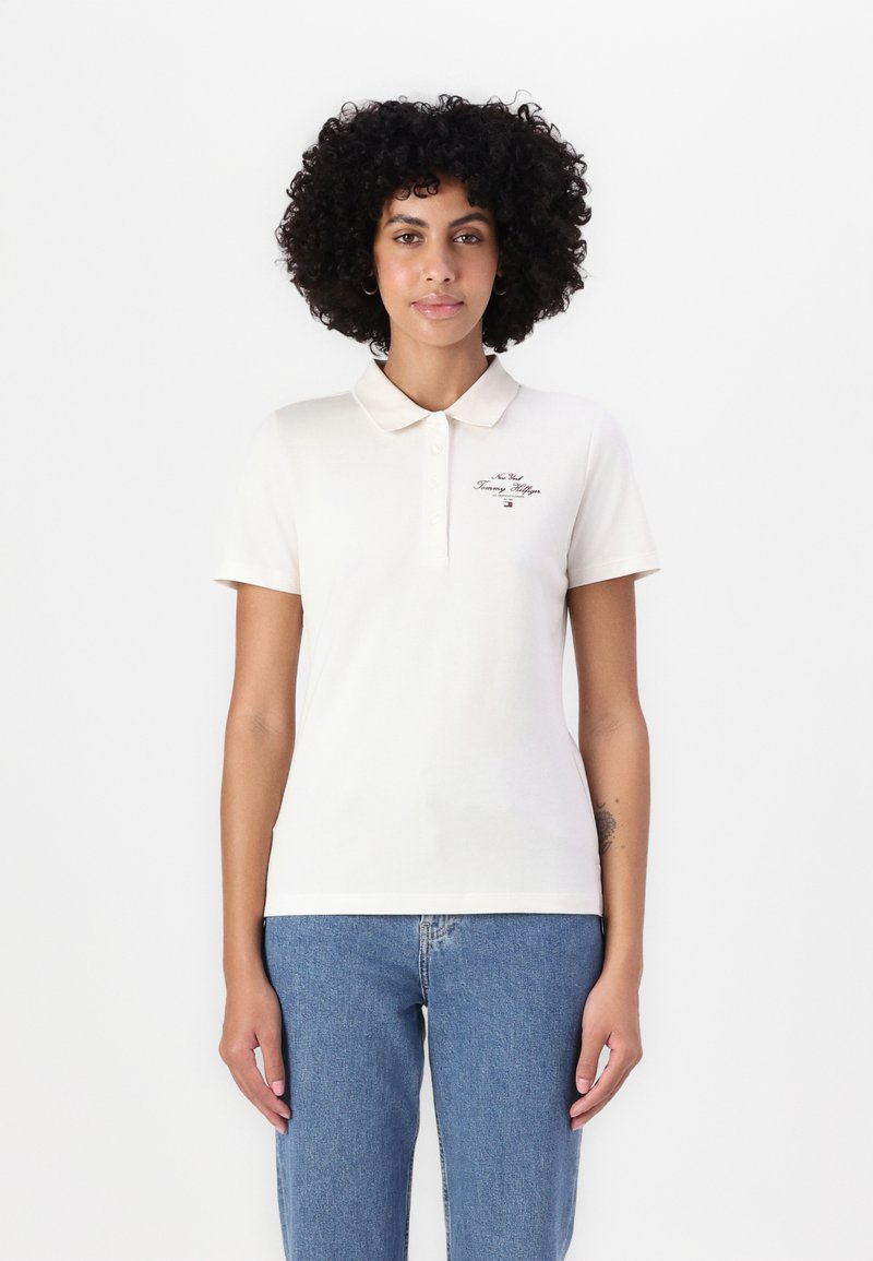 Polo in cotone beige con colletto classico, maniche corte, pattina con bottoni frontale e logo ricamato sul petto sinistro.