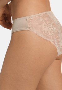 Biancheria intima beige con una parte anteriore in tessuto liscio e un intricato dettaglio in pizzo floreale sul retro, caratterizzata da una fascia morbida e bordi senza cuciture.