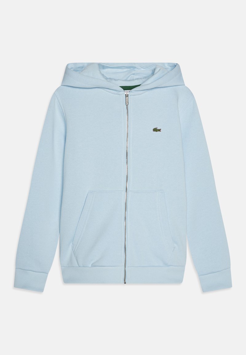 Sweatshirt azul claro com fecho, feito de tecido macio, com um bolso frontal e punhos canelados. Pequeno logotipo verde na área do peito esquerdo.