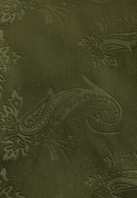 Tume roheline kangas, millel on kõrgendatud lille- ja paisleimuster, luues peene tekstuuriga pinna.