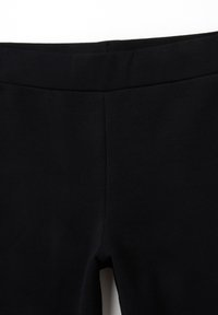 Leggings negros hechos de un tejido suave y elástico, con una cintura lisa y sin costuras ni bolsillos visibles, con un acabado mate.