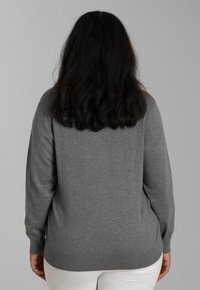 Pulover gri dintr-un material tricotat moale, cu un guler rotund, mâneci lungi și tiv dublat. Design simplu, fără modele sau accente.