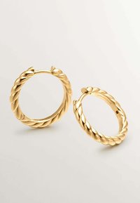 Pendientes de aro de oro con una textura retorcida y un acabado suave. Tienen forma circular y un cierre seguro. Destacan por su diseño dimensional.