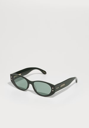 Occhiali da sole neri in plastica con lenti verdi. Il design del telaio angolare presenta dettagli in oro e piccoli punti sulle tempie.