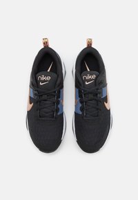 Černé tenisky Nike s texturovaným síťovaným svrškem, modrými a oranžovými akcenty, plochými šňůrkami a polstrovanou bílou podrážkou. Logo na jazyku a boku.