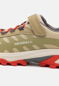 Zapatilla de running Merrell en beige y verde, con un upper texturizado, acentos rojos y una suela acolchada con un dibujo en el taqueado para mayor agarre.