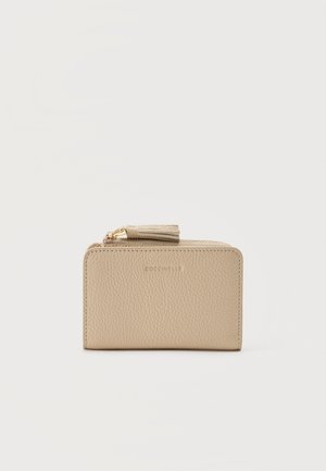 Beige tekstureret læderpung med guldlynlås og kvasttryk, kompakt rektangulær form, præget mærkenavn på forsiden.