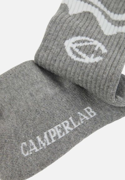 Chaussettes grises côtelées avec le texte blanc "CAMPERLAB" sur la semelle et un logo circulaire blanc près du bord.