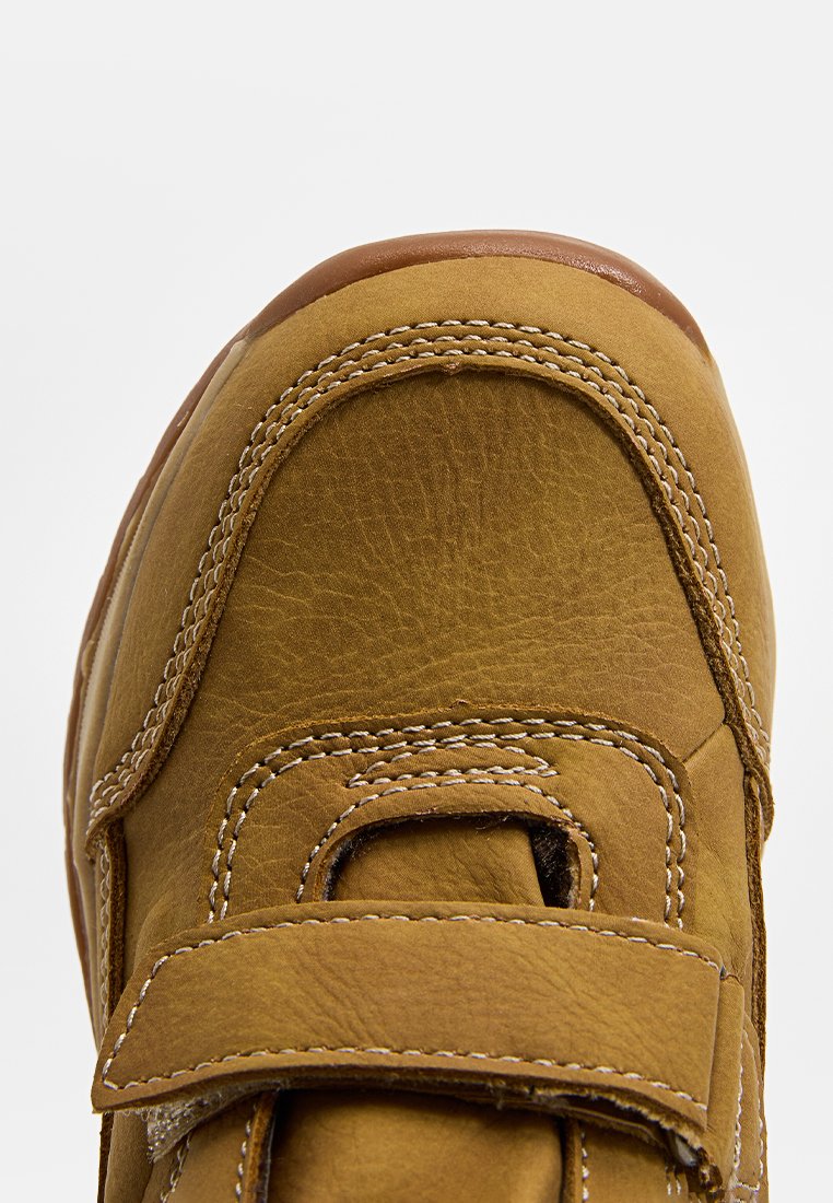 Braunes Leder Schuhe mit einer strukturierten Oberfläche, ausgestattet mit einem breiten Klettverschluss, verstärkten Nähten und einem runden Zehen-Design.