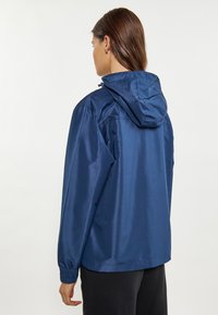 Blå vandtæt jakke med hætte, lavet af skinnende stof. Har elastiske manchetter og et enkelt, udekoreret design.