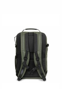 Mochila verde y negra con correas de malla acolchadas, un asa en la parte superior y un bolsillo con cremallera en el lateral. La textura del tejido es suave y duradera.