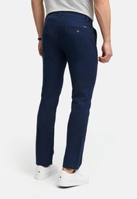 Chino navy din țesătură ușoară, cu croială dreaptă, având buzunare aplicate, detalii cu nasturi și un talie medie, asortat cu adidași albi.