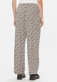 Pantaloni a gamba larga in un motivo geometrico crema e nero, con vita alta e una texture liscia, dal fit morbido.