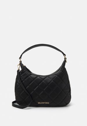 Black quilted leather handbag with a curved design, featuring a top zipper and a detachable strap. Gold logo accent on the front.