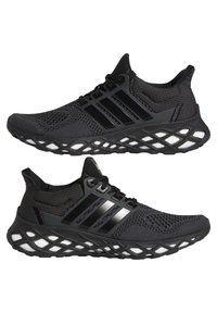 Chaussures de course en maille noire avec semelle matelassée à motif en treillis et design brillant à trois bandes sur les côtés, présentées en vue latérale.