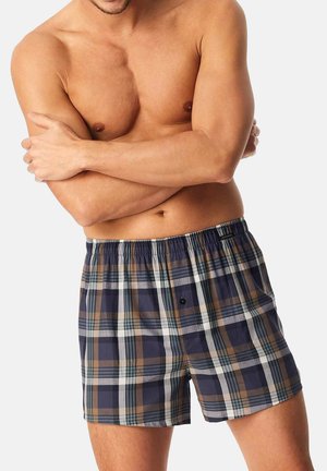 Boxer in plaid nei colori blu navy, marrone e bianco. Realizzati in tessuto traspirante, con una vita elastica e un dettaglio con un singolo bottone.
