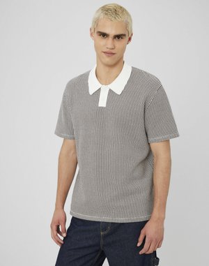 Polo à manches courtes avec un motif à carreaux noir et blanc, col blanc contrasté, coupe décontractée et texture de tissu douce.