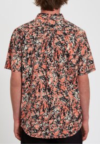 Chemise à manches courtes présentant un motif abstrait en corail, noir et blanc. Fabriquée en tissu léger avec un ourlet arrondi et un empiècement au dos.