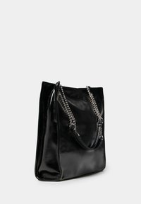 Borsa tote in similpelle nera con manici a catena argentata, di dimensioni medie, design elegante, texture liscia e apertura superiore senza chiusure visibili.