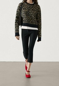 Yksivärinen leopardi-kuosisifoni mustalla pohjalla, kulunut helmakaulus; valkoinen paita alla, yhdistetty mustiin 7/8-housuihin ja punaisiin nilkkastrap-kengiin.