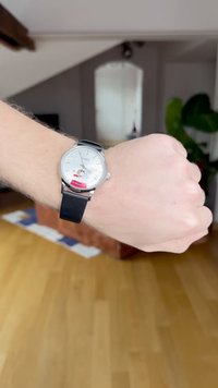 Personne portant une montre-bracelet Timex avec un bracelet en cuir noir et un personnage Snoopy sur le cadran blanc de la montre.