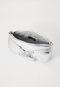 Borsa a mano metallica argento con chiusura a zip, caratterizzata da una superficie testurizzata e dettaglio con lacci sul davanti. Interno foderato in tessuto grigio.