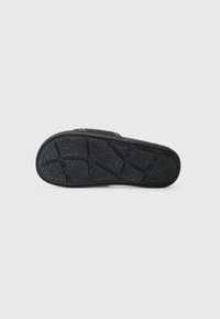 Black rubber sandal sole featuring a textured grip pattern, curved shapes, and lines for enhanced traction.