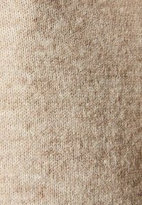 Tessuto lavorato a maglia beige con una superficie morbida e testurizzata. Toni variabili creano un motivo sottile, adatto per abbigliamento caldo o accessori.