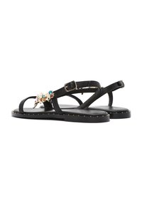 Sandali in pelle nera con cinturini sottili, decorazioni decorative, suola piatta e borchie dorate lungo i bordi.