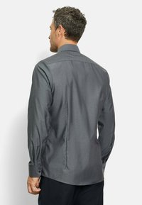 Graues Langarmhemd mit Button-Down-Kragen, aus texturiertem Stoff und mit Zweiknopfmanschetten. Rückansicht des Hemdes sichtbar.