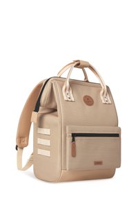 Zaino marrone chiaro con tessuto testurizzato, manico superiore, spallacci regolabili, tasca frontale con zip e una patch rotonda con logo. Presenta tre bande decorative.