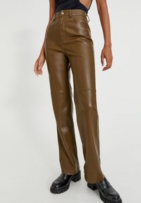 Pantalons taille haute en simili cuir marron à jambe droite, dotés d'une fermeture éclair sur le devant, de coutures visibles et d'une texture mate.