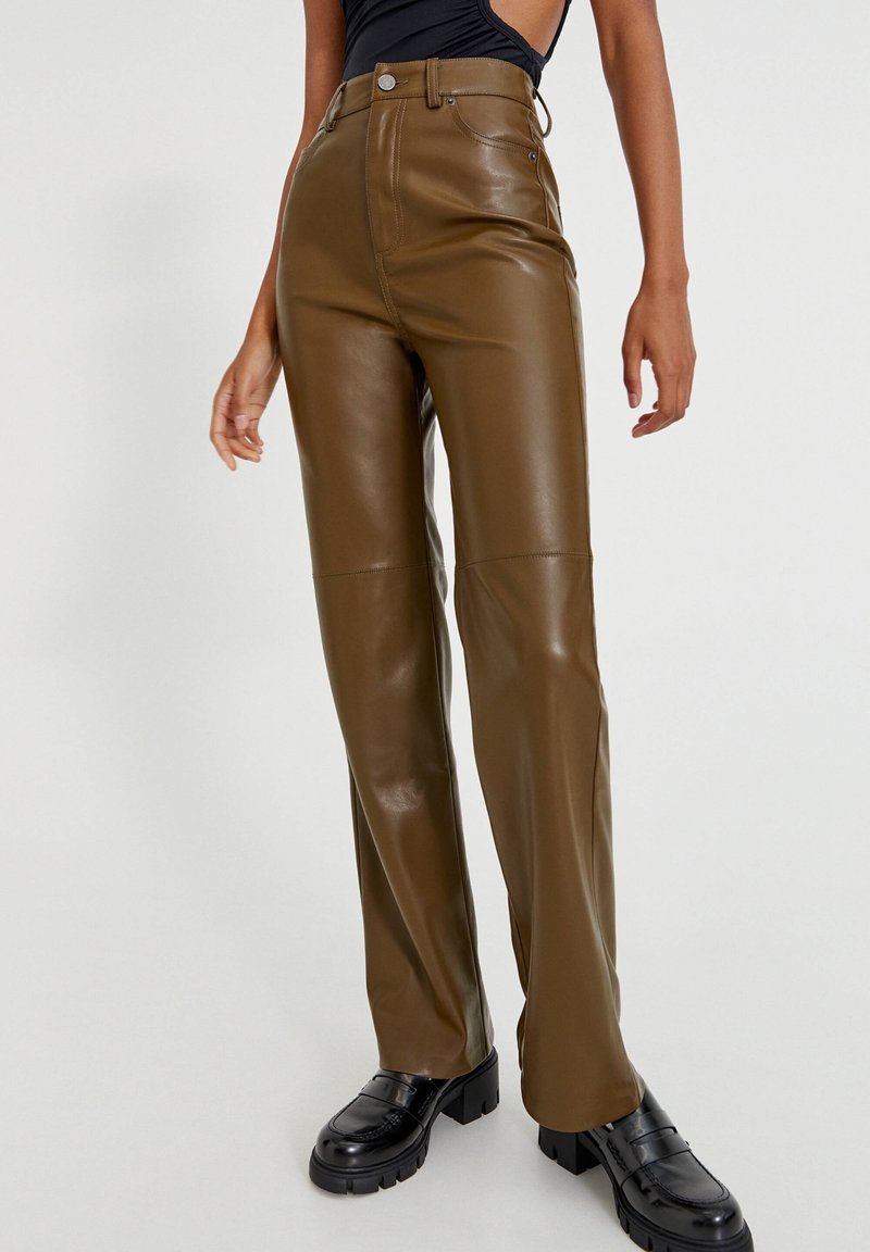 Pantalons taille haute en simili cuir marron à jambe droite, dotés d'une fermeture éclair sur le devant, de coutures visibles et d'une texture mate.