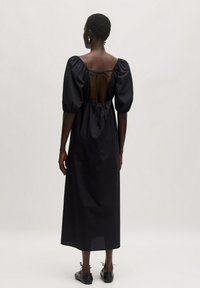 Schwarzes, knielanges Kleid mit Puffärmel, offener Rückseite, die mit einem Band gebunden ist, aus glattem Stoff, mit lässiger Passform und schickem Design.