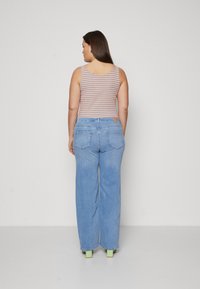Striped tank top in orange and blue paired with light blue wide-leg jeans. Features back pockets and green platform heels.
