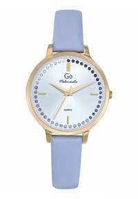 Montre ronde en quartz avec un cadran argenté, un boîtier doré, un bracelet en cuir lavande et des accents en cristal bleus et violets autour du cadran.