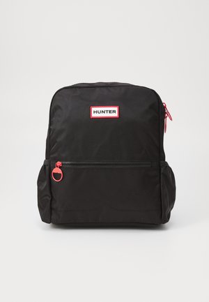 Svart ryggsäck tillverkad av slitstark nylon, med en röd dragkedja, framficka och en framträdande vit och röd "HUNTER"-logotyp på framsidan.