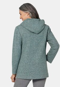 Kapuzenshirt aus strukturiertem, hellblauem Stoff. Verfügt über eine lockere Passform, lange Ärmel und ein mittellanges Design.