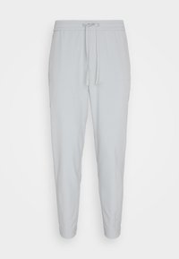 Pantalon de survêtement gris clair fuselé avec taille élastique et cordon, avec chevilles côtelées et poches latérales.