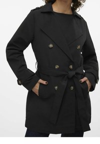 Gabardina negra con cierre de botones dobles, cinturón en la cintura y hombreras en los hombros. Cuenta con dos bolsillos laterales y mangas largas.