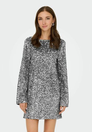 Robe en sequins argentés avec des manches longues, un col rond et une forme évasée, présentant une surface texturée et réfléchissante avec une coupe à hauteur des genoux.