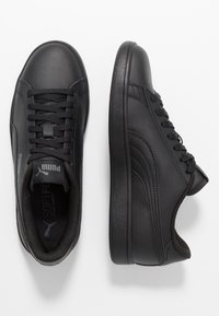 Sneakers neri in pelle sintetica con punta rotonda, suola in gomma testurizzata, stringati davanti e dettagli di cucitura. Presentano accenti del logo Puma.