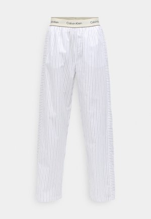 White pajama pants with navy vertical stripes, elastic waistband with "Calvin Klein" label, straight-cut legs, and soft cotton fabric.